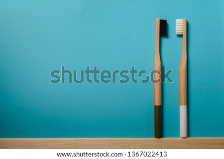 black and white colours bamboo toothbrushes on blue background.
Place for text. Ecoproduct.   eco-friendly