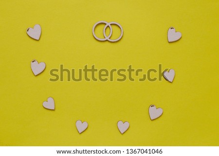 Wedding card design with wooden hearts and wedding rings on yellow background. Greeting wedding card with copy space.