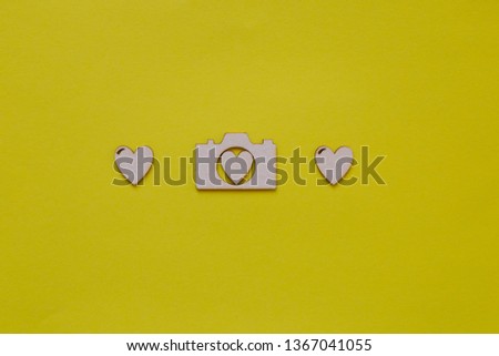 Greeting card for photographer, concept of photographer's day celebrating. Wooden photo camera and hearts on yellow background, copy space.