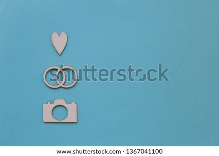 Card photography with wedding rings, heard and camera. Concept of decoration, wedding photography, present, blue background, copy space.