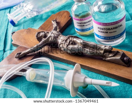 Vial with doses of pentobarbital next to a crucifix, Debate between life and death, religious belief in the face of euthanasia, conceptual image Royalty-Free Stock Photo #1367049461