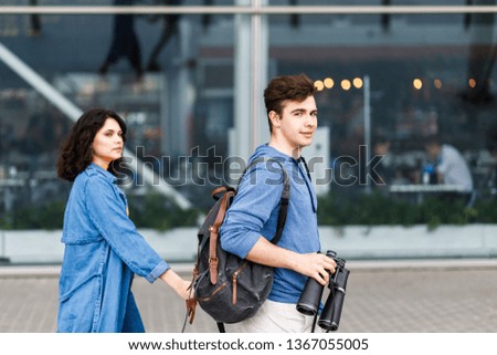 Young pretty couple - a boy and a girl walking around the city with a binocular in his hands. Young people travel.