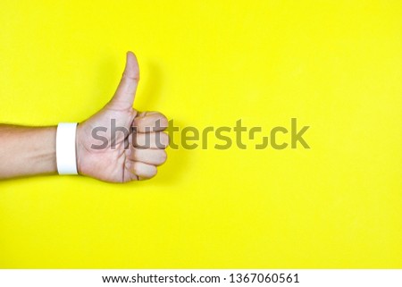 Top view of hand of showing thumbs up with empty wristband on colorful pastel on background view. Flat lay creative ideas on copy space.