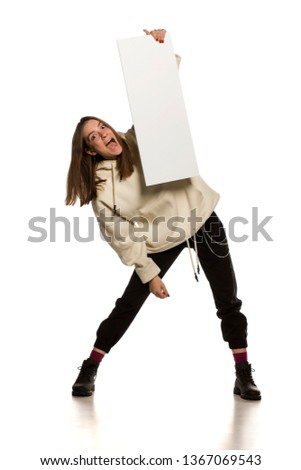 Young model in hoodie holding an empty advertising board on white background