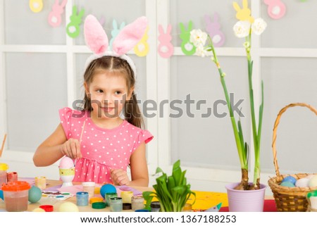 little child girl with Easter bunny ears painting Easter eggs at home. adorable child prepare for easter. Happy easter