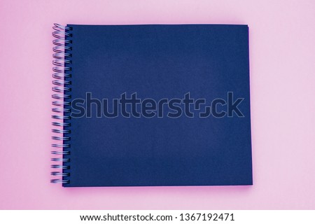 Photo album on pink background. Black spiral paper notebook, copy space, text place. Dark gray paper backround. Black notebook paper. 