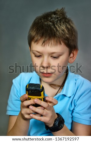 A boy of nine, using a mobile phone, reading a message