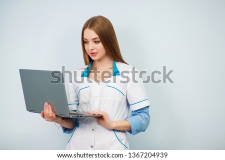 Happy female doctor using tablet computer isolated on a white background. Beautiful girl in a white coat. Copy space