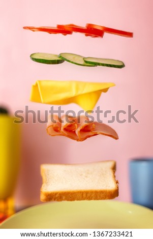 Fresh sandwich with flying ingredients isolated on pink background.