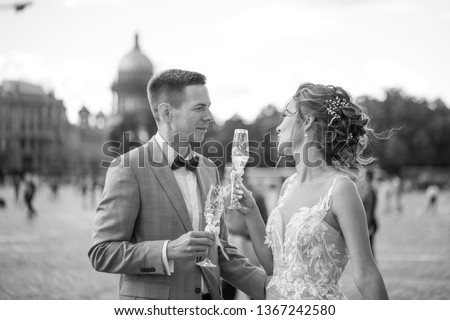 Bride and groom with glasses of champagne on the Palace Square in St. Petersburg