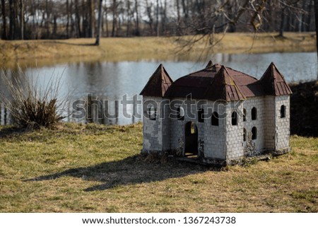 Doghouse in shape of a castle on the river bank in a park