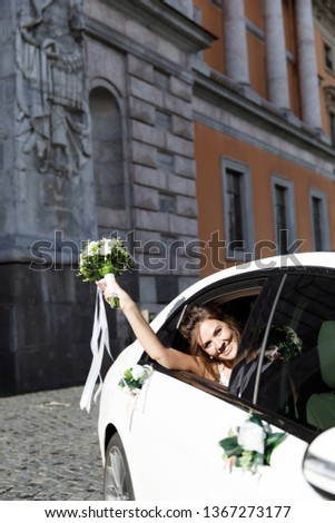 Happy bride looks out of the window of the wedding car