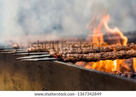 Traditional Adana kebab grilled on a bbq with orange coloured flame and smokes in Orange Blossom Carnival in Adana-Turkey