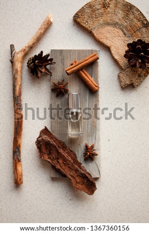 Perfume bottle with cinnamon sticks, anise stars, some bark and wood on a light background Royalty-Free Stock Photo #1367360156
