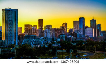 Denver Colorado skyline cityscape yellow golden hour sunrise over modern skyscraper condos in wide panoramic view of downtown modern bridges and high rise skyline view