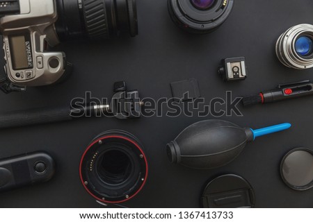 Photographer workplace with dslr camera system, camera cleaning kit, lens and camera accessory on dark black table background. Hobby travel photography concept. Flat lay top view copy space