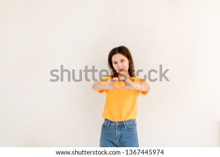 Beautiful Asian woman confident in a yellow sweater and jeans on a white background.