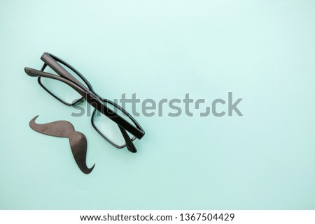Happy Father's day concept. Sign of mustache with glasses isolated on pastel blue background. Simple minimalism flat lay top view copy space. Man silhouette symbol