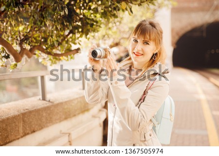Tourist young girl photographer takes photo on small camera while traveling, smiles and laughs.