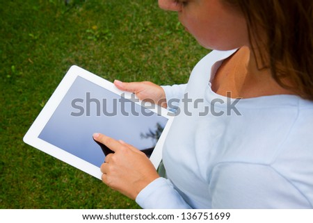 woman holding tablet PC on green grass lawn