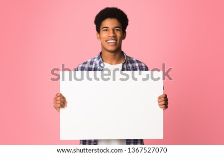 Happy guy showing blank placard with copy space for your text, pink background