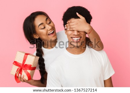 Surprise for you. Girl covering boyfriend eyes on pink background