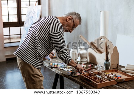Table with paints. Professional experienced artist standing near the table with paints before starting painting
