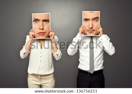man and woman holding photos with amazed faces
