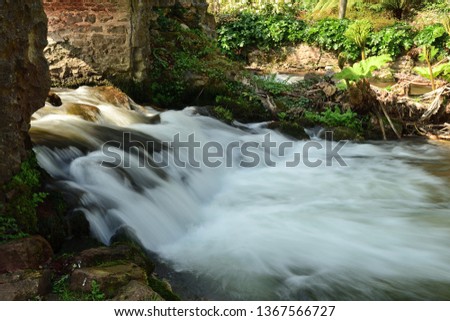Long exposure of a waterfall flowing under a bridge