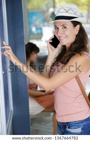 woman on the phone waiting for bus at stop