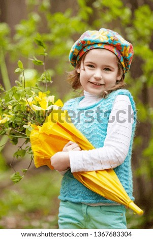 Little cute girl with narcissus flowers in a spring garden.  Children with flower bouquet playing outdoors. 