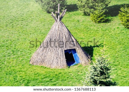 Straw wigwam on a glade on a sunny spring day. Wigwam type thatch huts .