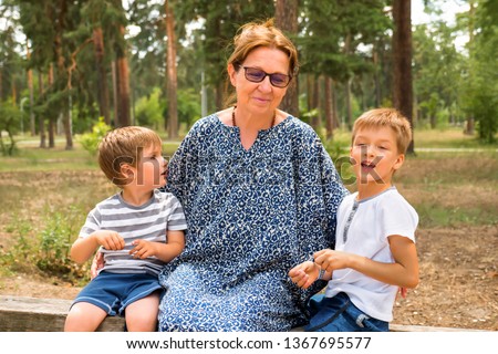 Two cute boys talking with nurse, grandmother. Kids laughing in the park, garden, forest. One parent family. Siblings love. Siblings talks. Happy children background. Family relationships. Mother Day