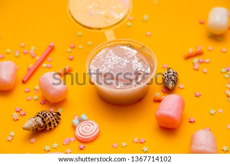 
children's toy multicolored slime with balls, glitters and additives. stretched slam on a yellow background. children's hands pulling mucus. Slime in a plastic can
