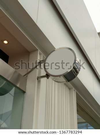 Blank round signboard hanging against white building background. Interior design detail.