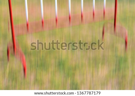 blurry red and white iron barrier on green grass lawn as background