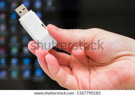 Hand holding one USB flash drive. A female hand holding a USB flash drive before the laptop.
