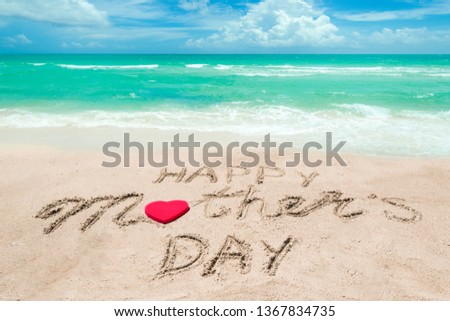 Happy Mother's day background on the sandy beach near the ocean with hearts. Hand drawn lettering typography