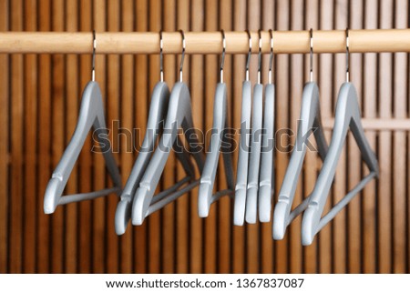 Empty hangers on rail against wooden background