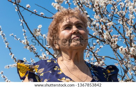 Grandmother on the background of cherry blossoms