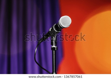 Stand with microphone on color background. Blurred lights