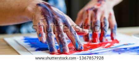 Contemporary art trend. Closeup of male hands creating abstract picture with red and blue acrylic paint on his finger tips.