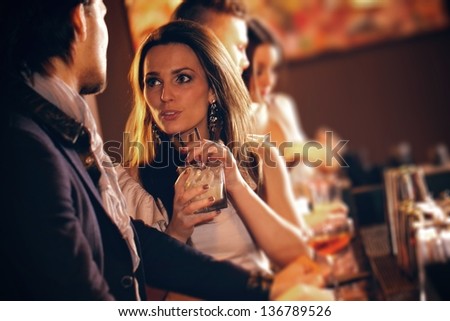 Young woman with a glass of wine talking to a man at the bar Royalty-Free Stock Photo #136789526