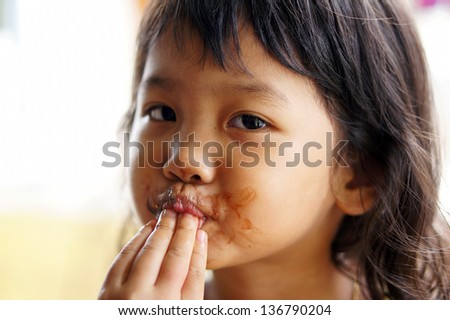 cute child licking a chocolate in her finger