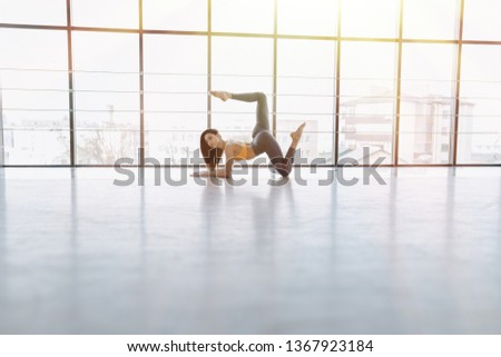 cozy young attractive girl doing fitness exercises with yoga on the floor against the background of panoramic windows