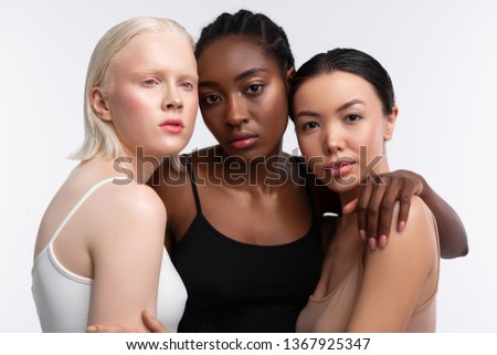 Light-skinned friends. African-American appealing woman standing between her light-skinned friends