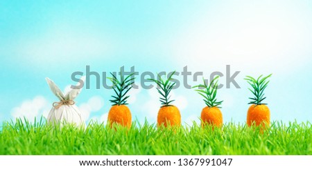 Easter egg wrapped in a paper in the shape of a bunny with carrot on green grass. Spring holidays concept.
