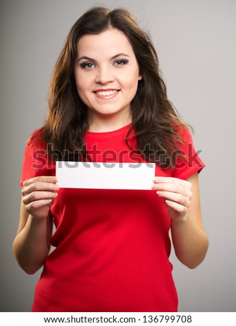 Portrait of young woman in a red shirt. Woman holds a poster. On a gray background
