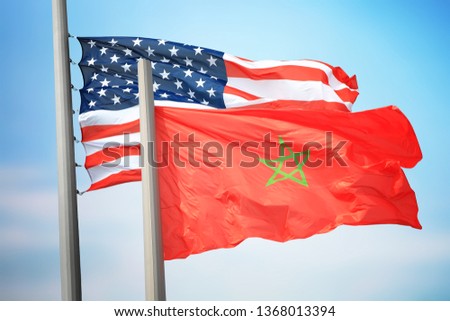 Flags of Morocco and the USA against the background of the blue sky