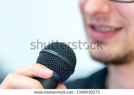 Microphone in the foreground, man taking into it in the blurry background